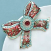 Accessoire mode femme : broche nœud colorée style bohème idéale pour égayer un manteau ou un pull